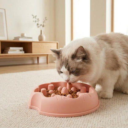 Chat utilisant une gamelle anti-glouton pour chat rose avec croquettes